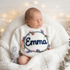 Sleeping baby wearing a white custom embroidered knit sweater with the name Emma.