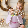 Child reaching into a purple Easter basket with bunny ears, named Emma.