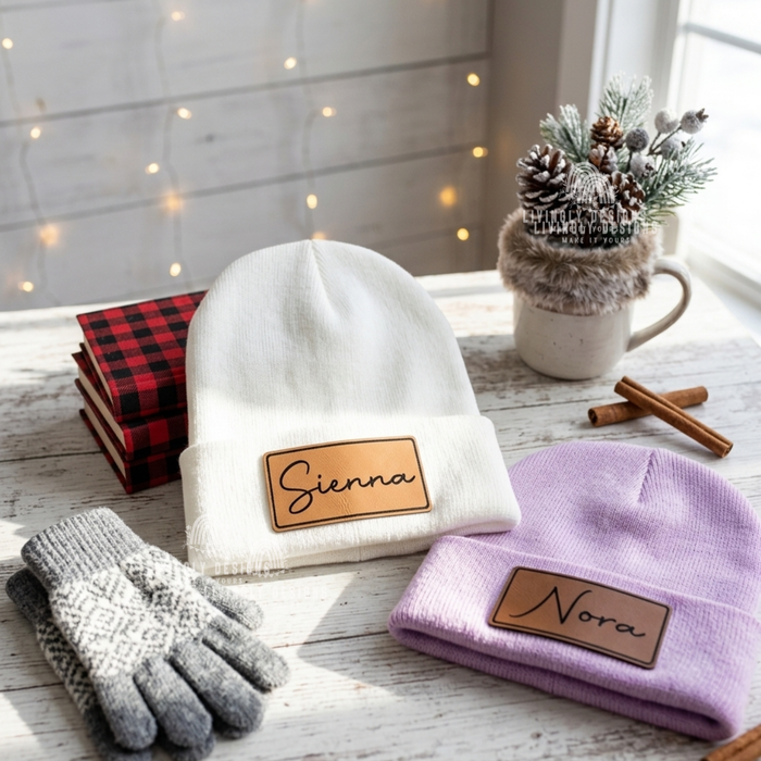 White and lavender beanies with leather patches named Sienna and Nora.