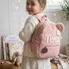 Child wearing a pink teddy bear backpack named Nora.