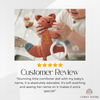 Customer review photo of a baby holding a rust-colored fox-shaped comforter with a teething ring, personalized with the name "Ethan," with a five-star review below.
