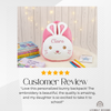 5-star customer review graphic featuring a plush pink bunny backpack embroidered with the name Clara, surrounded by books and colored pencils.