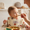 Baby wearing  bib named Linda being fed