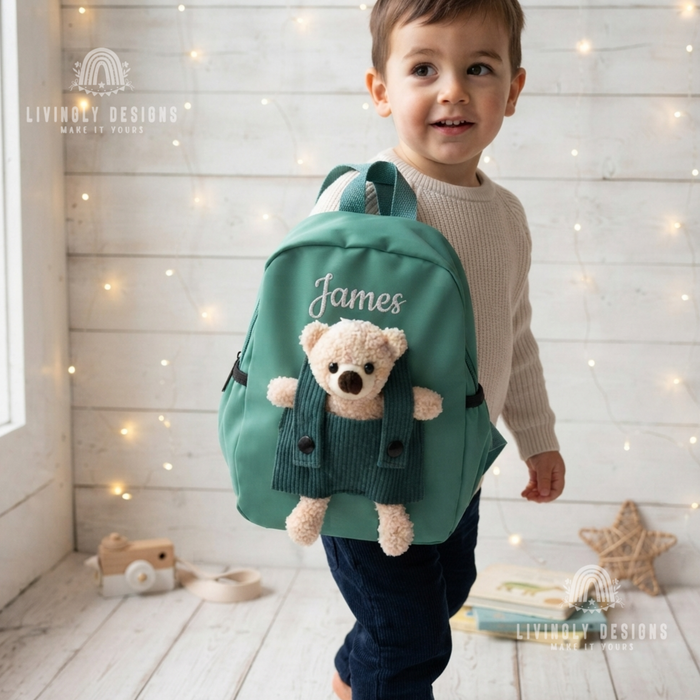Smiling toddler boy wearing a green backpack personalized with the name "James"