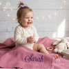 Baby sitting on a pink personalized blanket named Sarah, next to a bunny plush toy.