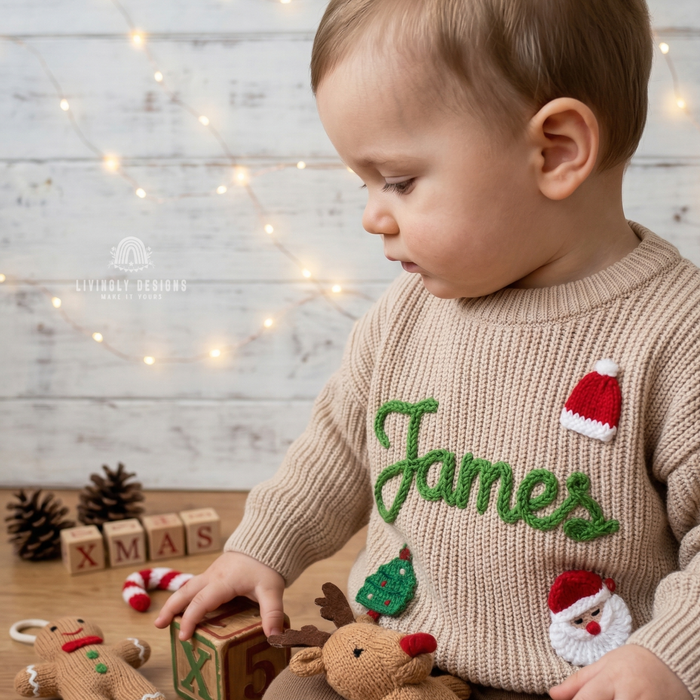 Child wearing a beige knitted Christmas sweater personalized with the name “James” and festive Santa, Christmas tree, and reindeer designs.
