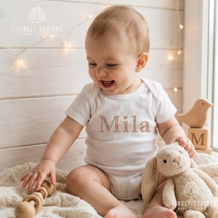 White onesie named Mila on a  smiling baby.