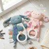 Teal and pink bunny-shaped baby comforters with teething rings, personalized with the names "Daisy" and "Bella," displayed on a table