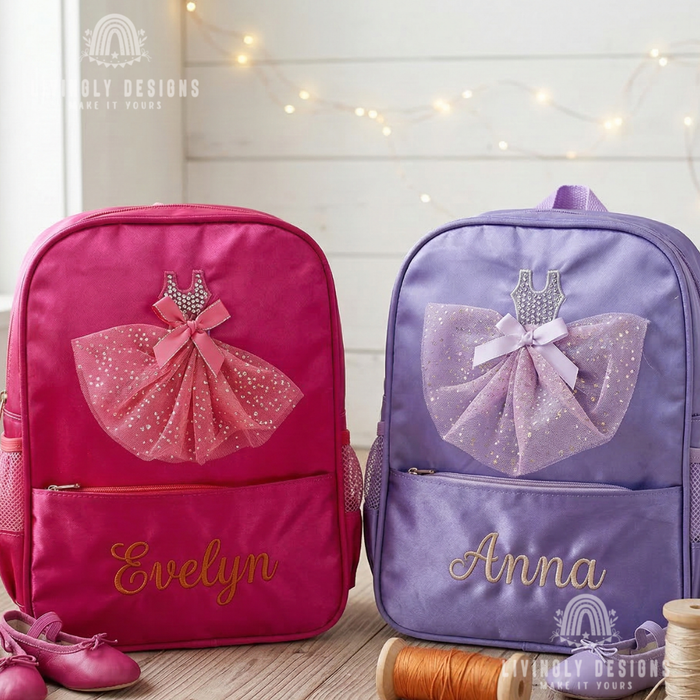Two personalized children's backpacks with ballet dress appliques, one hot pink named 'Evelyn' and one lavender named 'Anna', displayed on a wooden surface with pink shoes and spools of thread.