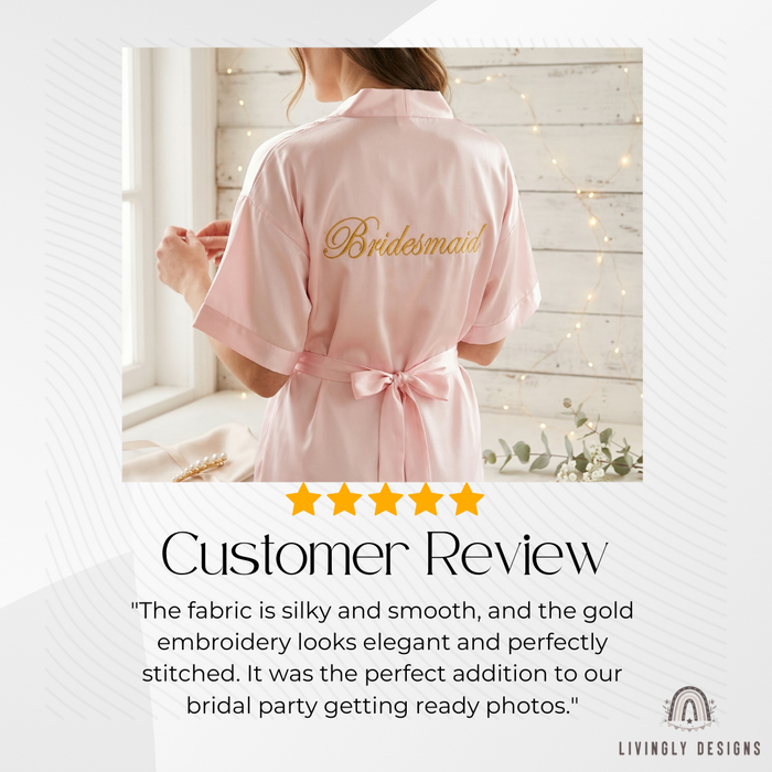 Woman wearing a pink satin robe embroidered with “Bridesmaid” on the back.