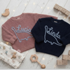Two sweaters with dinosaur embroidery named Lucia and Linda.
