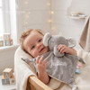 Baby lying in a cozy wooden bassinet holding a plush grey elephant security blanket embroidered with the name Julian in white script.