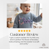 Smiling baby wearing a blue knit sweater personalized with the name "Clara"