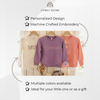 Cream, purple, and coral sweatshirts personalized with floral embroidered names, including "Cynthia" clearly visible on the purple sweatshirt, hanging on wooden hangers