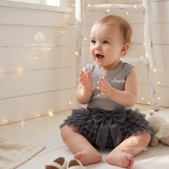 Baby wearing a grey ribbed tutu romper personalized with the name "Anna"