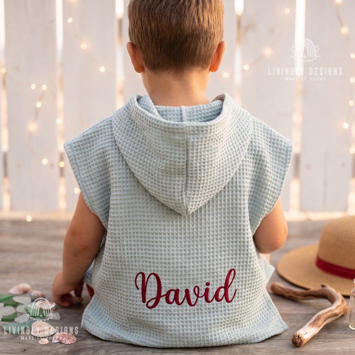 Back view of a child wearing a sage green hooded waffle bathrobe custom embroidered with the name David.