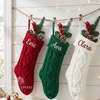 Red, green, and white knit stockings with the names "Evie," "Ava," and "Clara"
