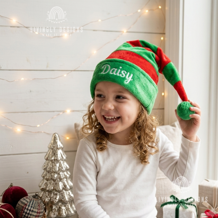 Girl wearing a green and red striped elf hat with the name "Daisy"