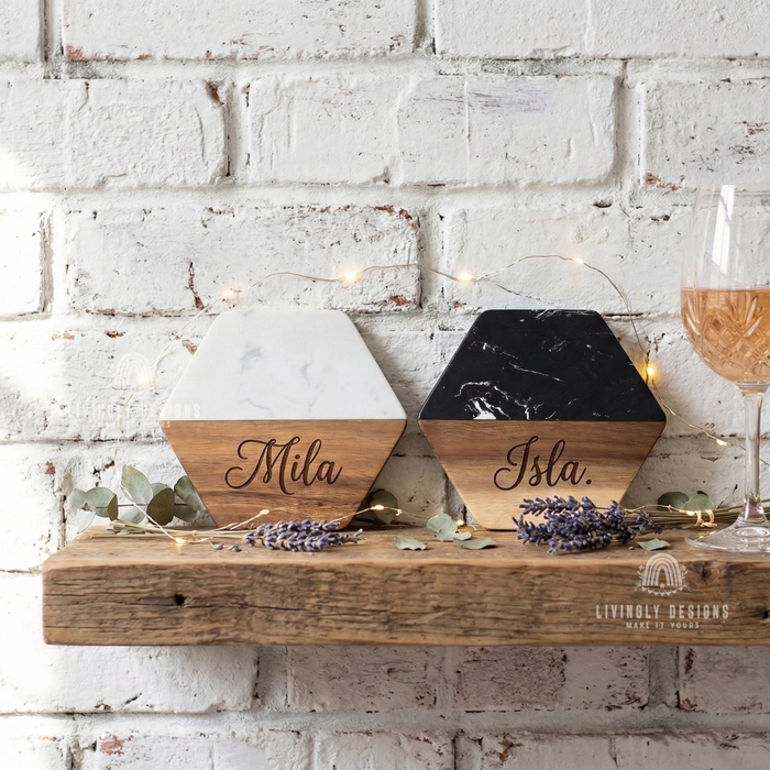 Two hexagonal marble and wood coasters engraved with the names "Mila" and "Isla," displayed on a wooden shelf