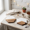 Two hexagonal white marble and wood coasters engraved with the names "Emmie" and "Jenna," displayed on a rustic wooden table