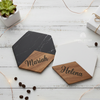 Two hexagonal marble and wood coasters engraved with the names "Mariah" and "Helena," styled on a white wooden surface