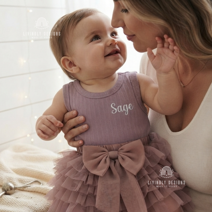 Baby wearing a mauve ribbed tutu romper personalized with the name "Sage"