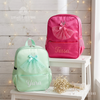 Mint green and pink backpacks with sparkly tulle ballerina dress appliqués, personalized with the names "Yara" and "Tessa," displayed on a white stool