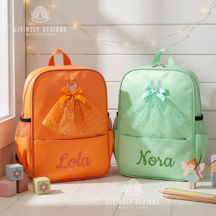 Orange and mint green backpacks with sparkly tulle ballerina dress appliqués, personalized with the names "Lola" and "Nora," displayed with a wooden fairy figure
