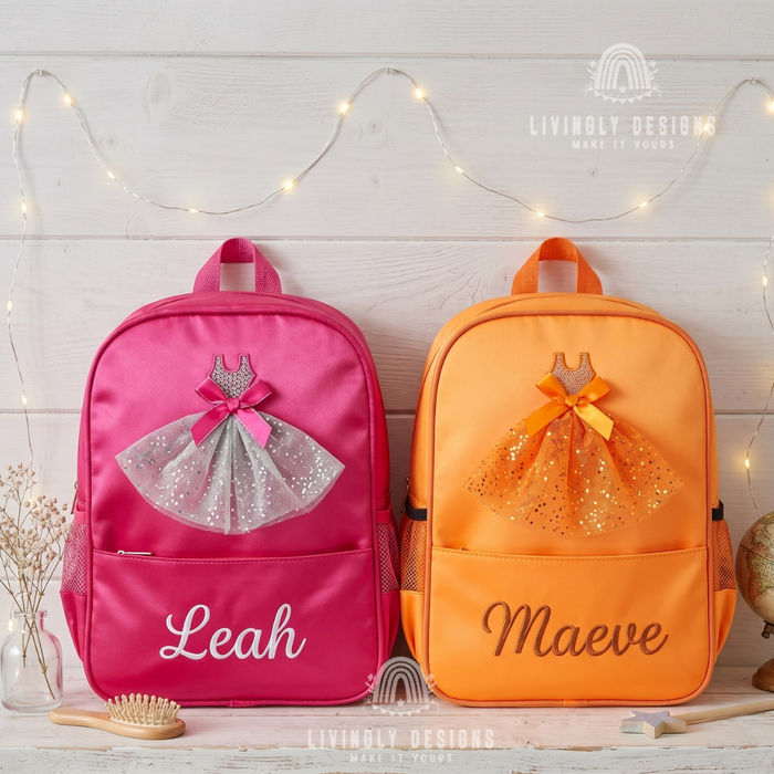 Pink and orange backpacks with sparkly tulle ballerina dress appliqués, personalized with the names "Leah" and "Maeve," displayed on a shelf