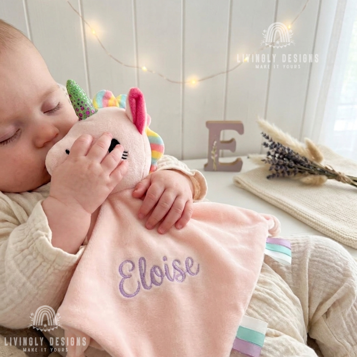 Baby holding pink unicorn security blanket named Eloise
